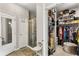 Bright main bathroom with glass shower and walk-in closet space with shelves and ottoman seating at 2417 Liner Ave, Apopka, FL 32703