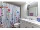 Well-lit bathroom has a single sink vanity, floral shower curtain, and tiled floors at 2500 Lee Rd # 243, Winter Park, FL 32789