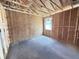 Unfinished bedroom with exposed framing, window, and concrete floor at 30166 Rustic Mill Street, Mount Dora, FL 32757