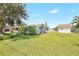 Landscaped backyard with green lawn, fencing, mature trees, and an additional storage structure at 338 Eastern Ave, St Cloud, FL 34769