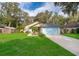 Single story home with a blue garage door, well-manicured lawn, and lovely landscaping at 39939 Parkinsonia St, Lady Lake, FL 32159