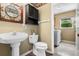 Charming half bathroom with pedestal sink, decorative mirror, and convenient access to the laundry room at 4830 Summerbridge Cir, Leesburg, FL 34748