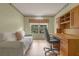 Well-lit home office with a large window, built-in cabinets, and comfortable seating area at 4830 Summerbridge Cir, Leesburg, FL 34748
