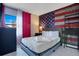 Comfortable bedroom featuring queen bed, red curtains, and an American flag accent wall at 6165 Carrier Dr # 2605, Orlando, FL 32819