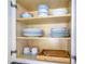 Organized kitchen cabinet featuring dinnerware sets, mugs, and a wooden silverware tray at 6165 Carrier Dr # 2605, Orlando, FL 32819