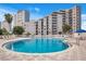 Resort style pool with lounge chairs and an upscale condo in the background at 6165 Carrier Dr # 2605, Orlando, FL 32819