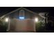 Two car garage with stucco facade, white door, modern lighting fixtures and address in clear view at night at 651 Oak Hollow Way, Altamonte Springs, FL 32714