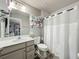 Well-lit bathroom with a single sink vanity, toilet, and shower featuring a white curtain, maximizing space and functionality at 6947 Cucamelon Ct, Windermere, FL 34786