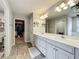 Modern bathroom featuring double vanity sinks, spacious countertop, a walk-in closet, and wood-look tile flooring at 6947 Cucamelon Ct, Windermere, FL 34786