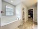 Bright bathroom showcasing a large soaking tub, a window for natural light, and a walk-in closet for convenience at 6947 Cucamelon Ct, Windermere, FL 34786