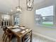 Dining area features a wood table, modern pendant lighting, and a view of the backyard pool through a large window at 6947 Cucamelon Ct, Windermere, FL 34786