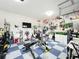 Spacious two car garage with a blue tiled floor, exercise equipment and plenty of wall art at 6947 Cucamelon Ct, Windermere, FL 34786