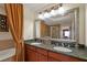 Bathroom featuring a double sink vanity with granite countertops and an ornate framed mirror at 7616 Cabana Ct # 301, Reunion, FL 34747