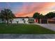 Charming single-story home with a well-manicured lawn, red front door and delightful sunset at 8120 Gondola Dr, Orlando, FL 32809