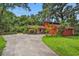 Inviting red home with a long driveway, mature trees, and well-maintained lawn at 874 Quarters Ct, Port Orange, FL 32129
