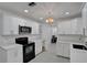 Bright kitchen featuring white cabinetry, quartz countertops, stainless steel appliances and decorative chandelier at 874 Quarters Ct, Port Orange, FL 32129
