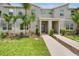Inviting two-story townhome with covered entrance, lush lawn and green shrubs surrounding a walkway to the front door at 8961 Cabot Cliffs Dr, Davenport, FL 33896