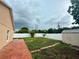 Spacious backyard featuring a red brick patio, vinyl fence, a small shed, and green space at 1001 Golfside Ct, Kissimmee, FL 34741