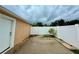 Enclosed backyard patio featuring a concrete slab, white fence, and convenient side door entrance at 1001 Golfside Ct, Kissimmee, FL 34741