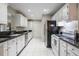 Galley kitchen with white cabinets, black countertops and appliances with tile flooring at 1405 Montclair Ct, Orlando, FL 32812