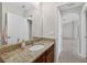Bathroom features a granite countertop, a large mirror, and a doorway leading to a hallway at 15318 Sandfield Loop, Winter Garden, FL 34787
