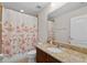 Well-lit bathroom featuring granite countertops, a shower with a floral curtain, and a vanity with a sink at 15318 Sandfield Loop, Winter Garden, FL 34787