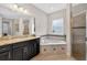 Bright bathroom with granite counters, dark cabinets, walk-in shower, and soaking tub at 15318 Sandfield Loop, Winter Garden, FL 34787