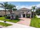 Beautifully landscaped two-story home featuring a brick driveway, lush lawn, and well-maintained greenery at 15318 Sandfield Loop, Winter Garden, FL 34787