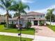 Beautifully landscaped two-story home featuring a brick driveway, lush lawn, and well-maintained greenery at 15318 Sandfield Loop, Winter Garden, FL 34787
