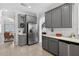 Kitchen featuring stainless refrigerator, gray cabinets, white countertops, tile flooring, and adjacent sitting room at 15318 Sandfield Loop, Winter Garden, FL 34787
