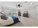Spacious primary bedroom featuring tray ceilings, neutral carpeting, large windows, and a ceiling fan at 15318 Sandfield Loop, Winter Garden, FL 34787