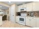 Kitchen with white appliances, tile backsplash, and adjacent dining area at 1921 Geronimo Trl, Maitland, FL 32751
