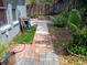 Landscaped backyard featuring a brick pathway, lush plants, and a wooden fence at 2474 Cimmaron Ash Way, Apopka, FL 32703