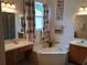 Bright bathroom featuring a garden tub, vanity, decorative accents, and ample counter space at 2474 Cimmaron Ash Way, Apopka, FL 32703