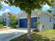 Exterior side view showcasing the attached two-car garage with blue door and well-maintained lawn at 2474 Cimmaron Ash Way, Apopka, FL 32703