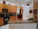 Kitchen with granite counters, wooden cabinetry, and a view into the adjacent dining room with table and chairs at 2474 Cimmaron Ash Way, Apopka, FL 32703
