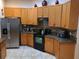 Kitchen featuring wood cabinets, granite countertops, stainless steel refrigerator, and tiled floors at 2474 Cimmaron Ash Way, Apopka, FL 32703