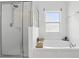 Relaxing bathroom with a large tub, glass-enclosed shower, and a bright window at 267 Williamson Dr, Davenport, FL 33897