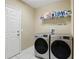 Modern laundry room with washer and dryer, storage shelves, and a bright white door at 267 Williamson Dr, Davenport, FL 33897