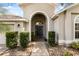 Close-up of the grand arched entryway featuring decorative shrubs and a neatly graveled walkway to the front door at 2696 Clearview St, Clermont, FL 34711