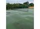 Outdoor tennis court with green surface, net, and fencing surrounded by tall trees at 2776 Curry Ford Rd # Ge, Orlando, FL 32806