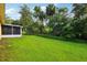 Spacious backyard with lush green lawn and a screened in patio at 395 Alcazar Ave, De Leon Springs, FL 32130