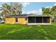 The backyard showcases the home's exterior with a screened porch and lush green lawn at 395 Alcazar Ave, De Leon Springs, FL 32130