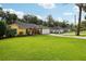 Charming yellow house featuring a well-manicured lawn, lovely landscaping, and an attached two-car garage at 395 Alcazar Ave, De Leon Springs, FL 32130