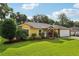 Charming yellow house featuring a well-manicured lawn, lovely landscaping, and an attached two-car garage at 395 Alcazar Ave, De Leon Springs, FL 32130