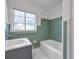 Classic bathroom with green tiling, a shower-tub combo, white hexagonal tile flooring, and a window at 441 S Primrose Dr, Orlando, FL 32803