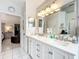 Bathroom with a dual sink vanity, large mirrors, and access to bedroom and hallway at 6902 Coral Cove Dr, Orlando, FL 32818