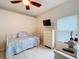 Well-lit bedroom features a ceiling fan, tile floor, closet, dresser, and a wall mounted TV at 6902 Coral Cove Dr, Orlando, FL 32818