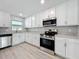 Well-lit kitchen with white cabinets, stainless steel appliances, and light wood flooring at 8676 Hillside Dr, Orlando, FL 32810