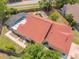 Aerial view of a home featuring a screened pool, brick pavers, well-maintained landscaping, and a charming, terracotta colored roof at 10360 Crystal Point Dr, Orlando, FL 32825
